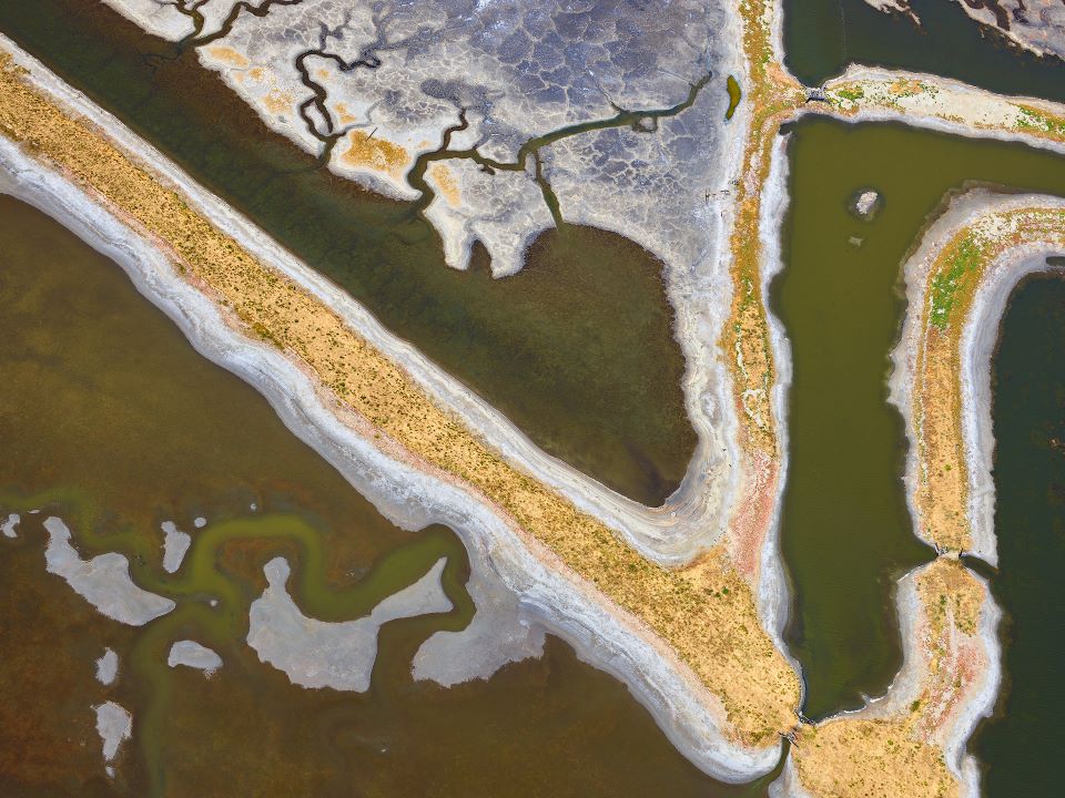 Aerial view of a coastal landscape with water bodies and sandy shores.