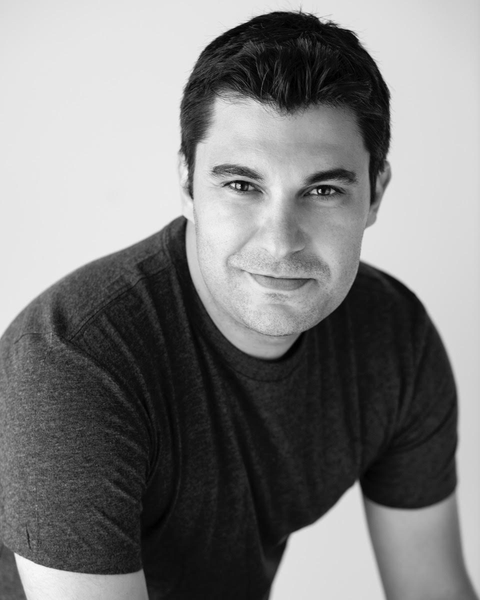 Black and white portrait of a man wearing a dark t-shirt against a plain background