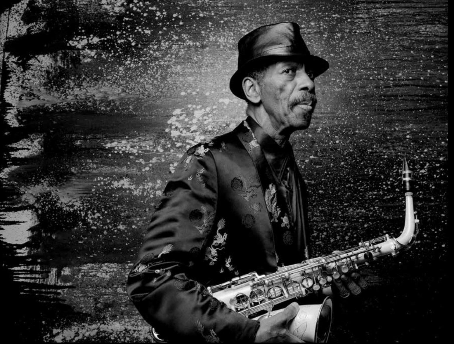 Man holding a saxophone with a textured black and white background