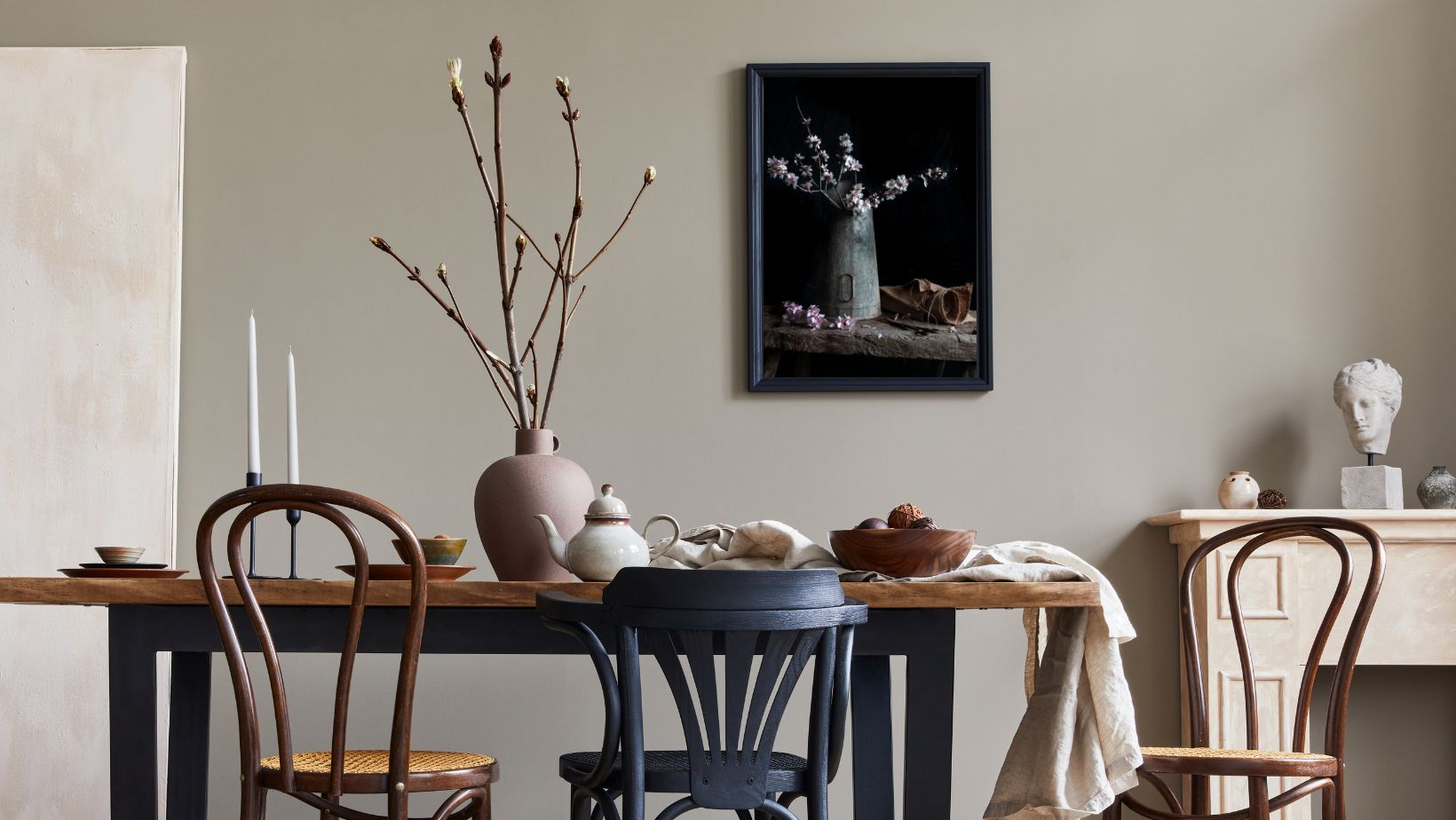 Dining room with wooden table, chairs, and decorative items on a neutral wall.