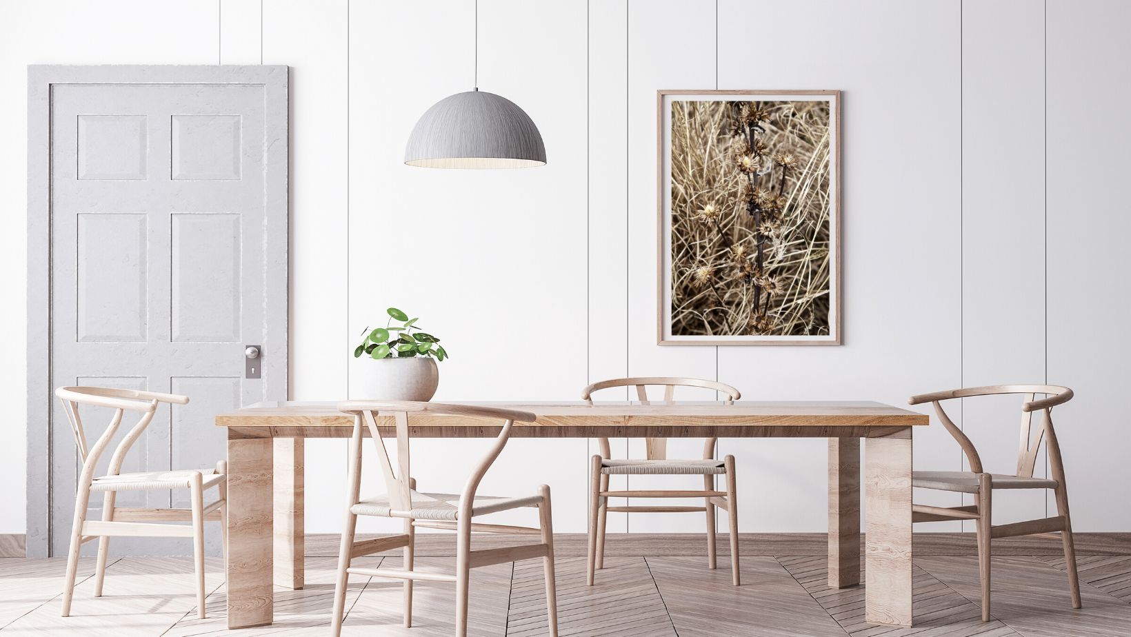 Dining area with wooden table and chairs against a white wall with a large framed nature photography print on the wall.