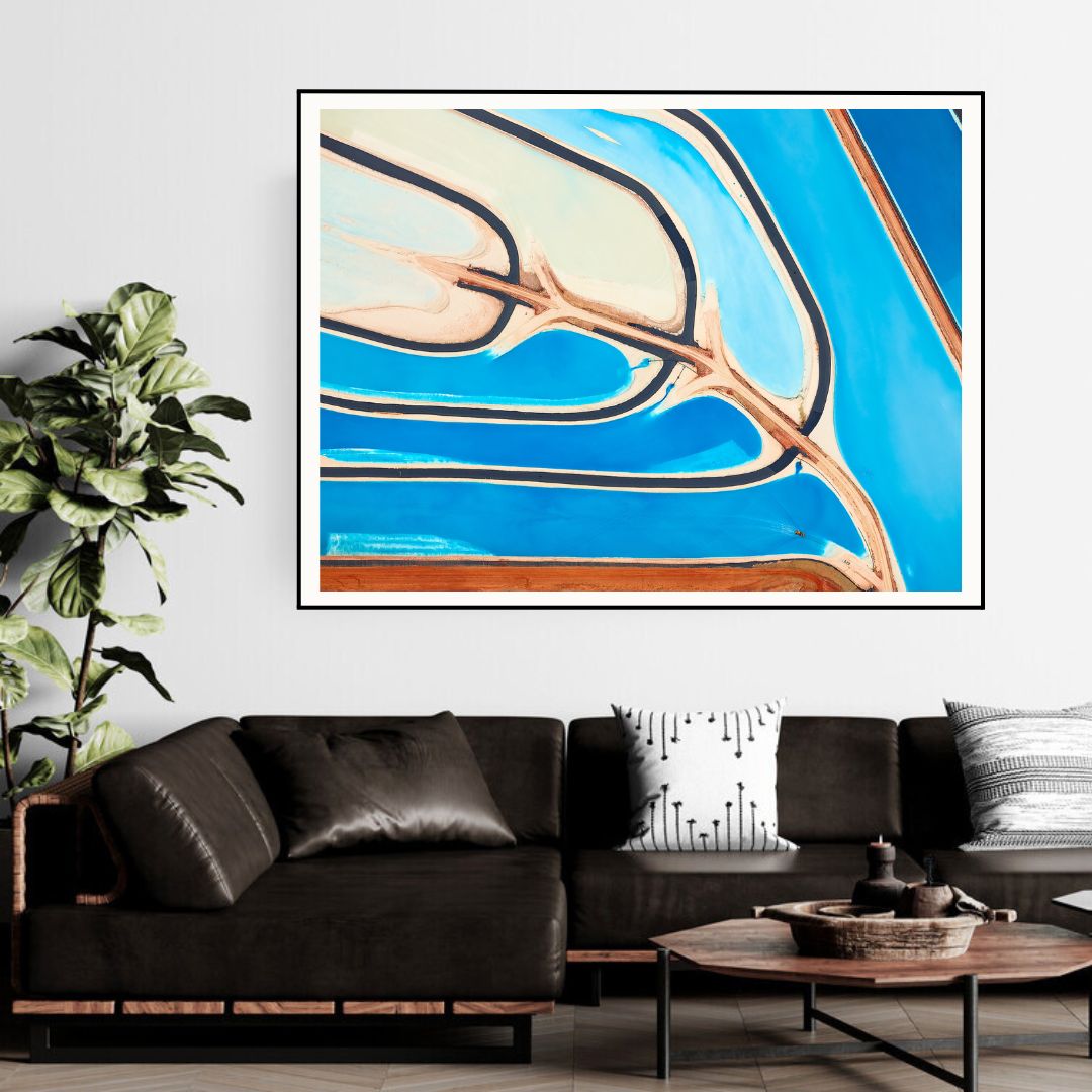 Abstract art print on a wall above a black sofa in a living room.