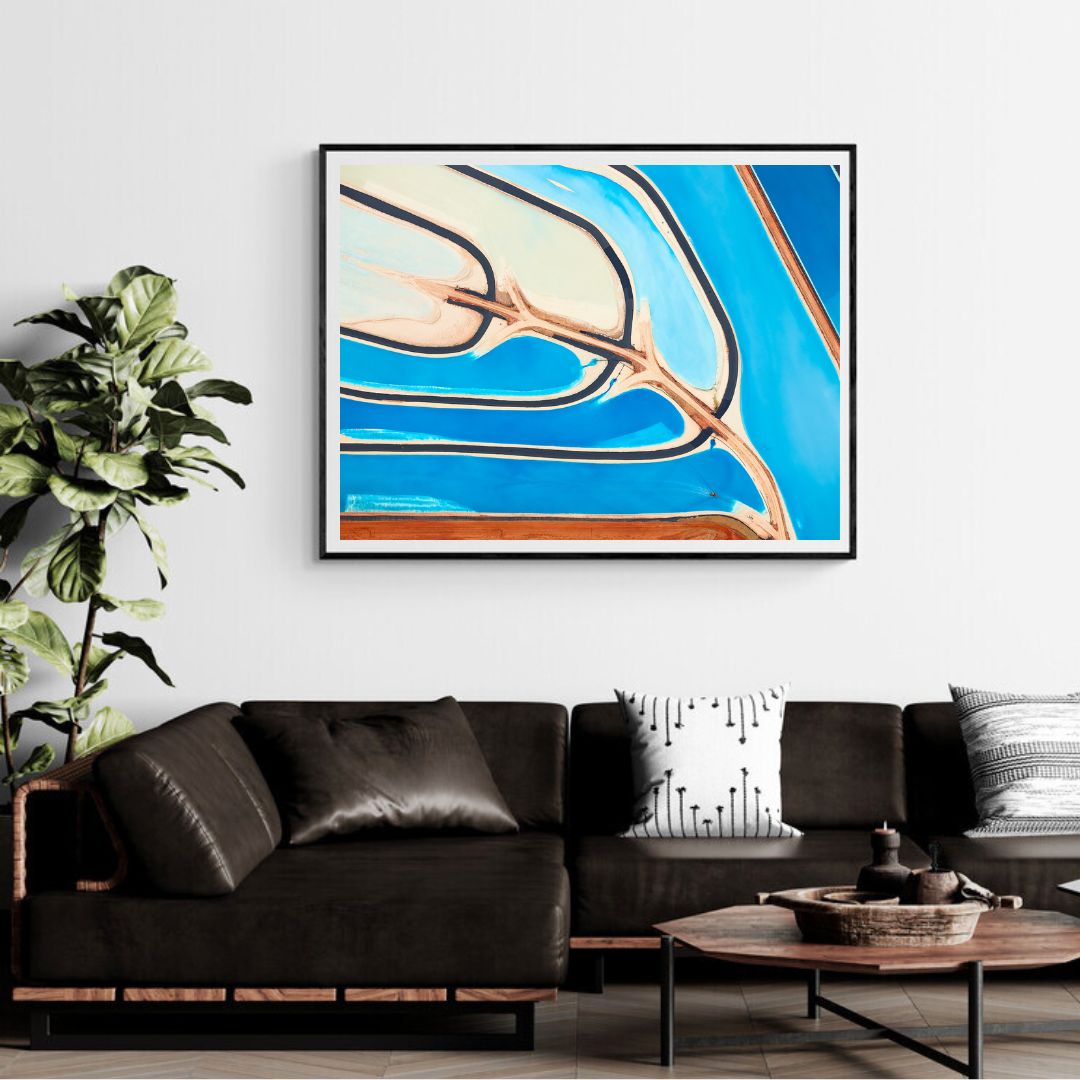 Living room with a black sofa, abstract art on the wall, and a plant.