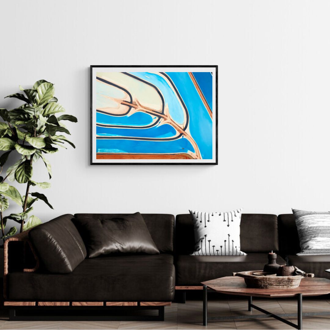 Modern living room with a black sofa, abstract art on the wall, and a plant.