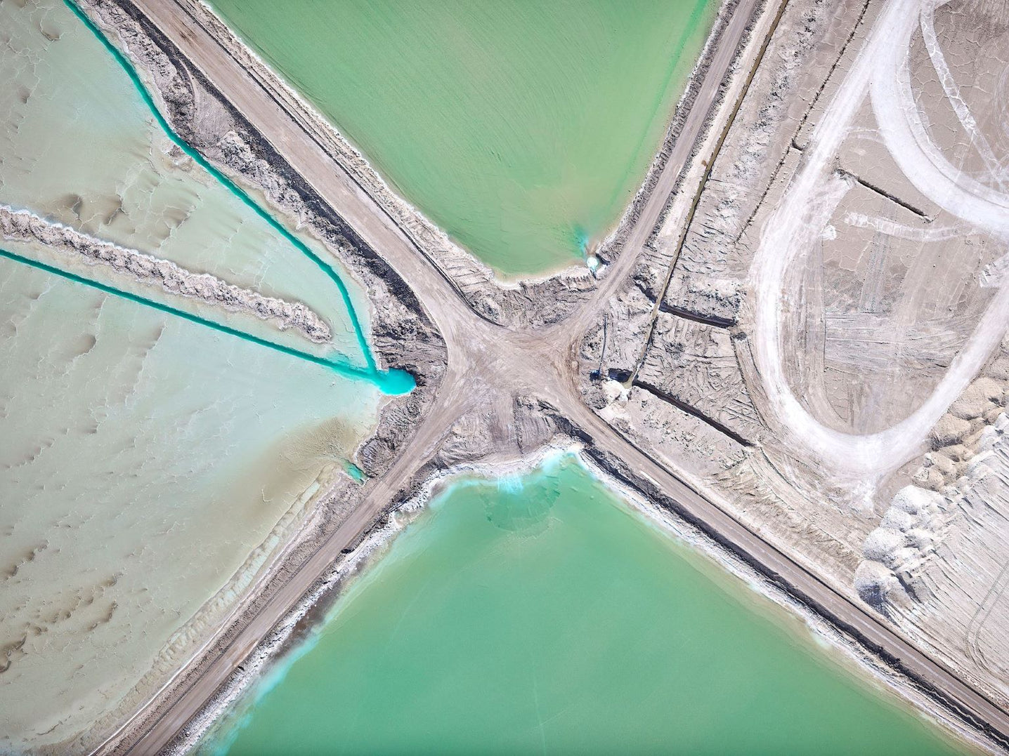 Aerial view of a road intersection with green water bodies on either side.