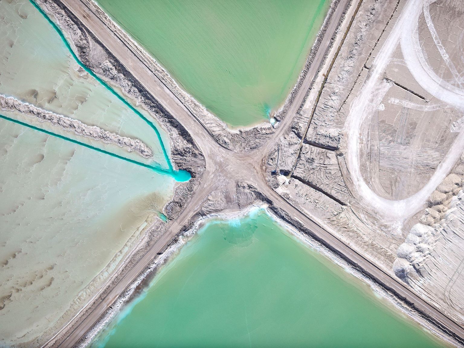 Aerial view of a road intersection with green water bodies on either side.