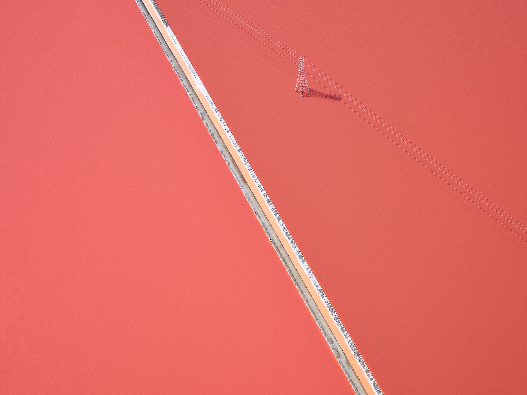 Aerial view of a straight road cutting through an orange landscape