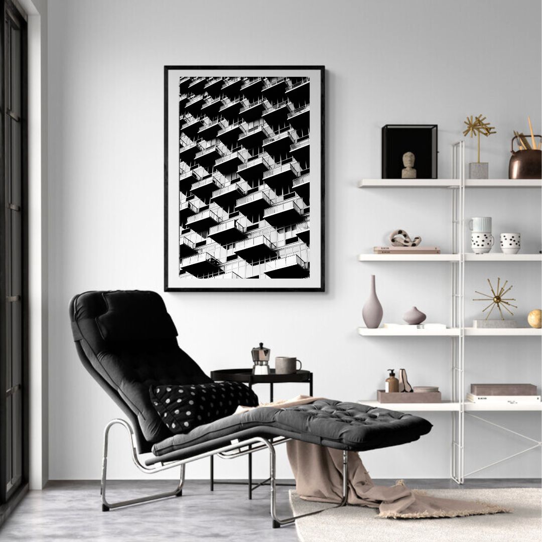 Modern living room with a black armchair, ottoman, and abstract art on the wall.