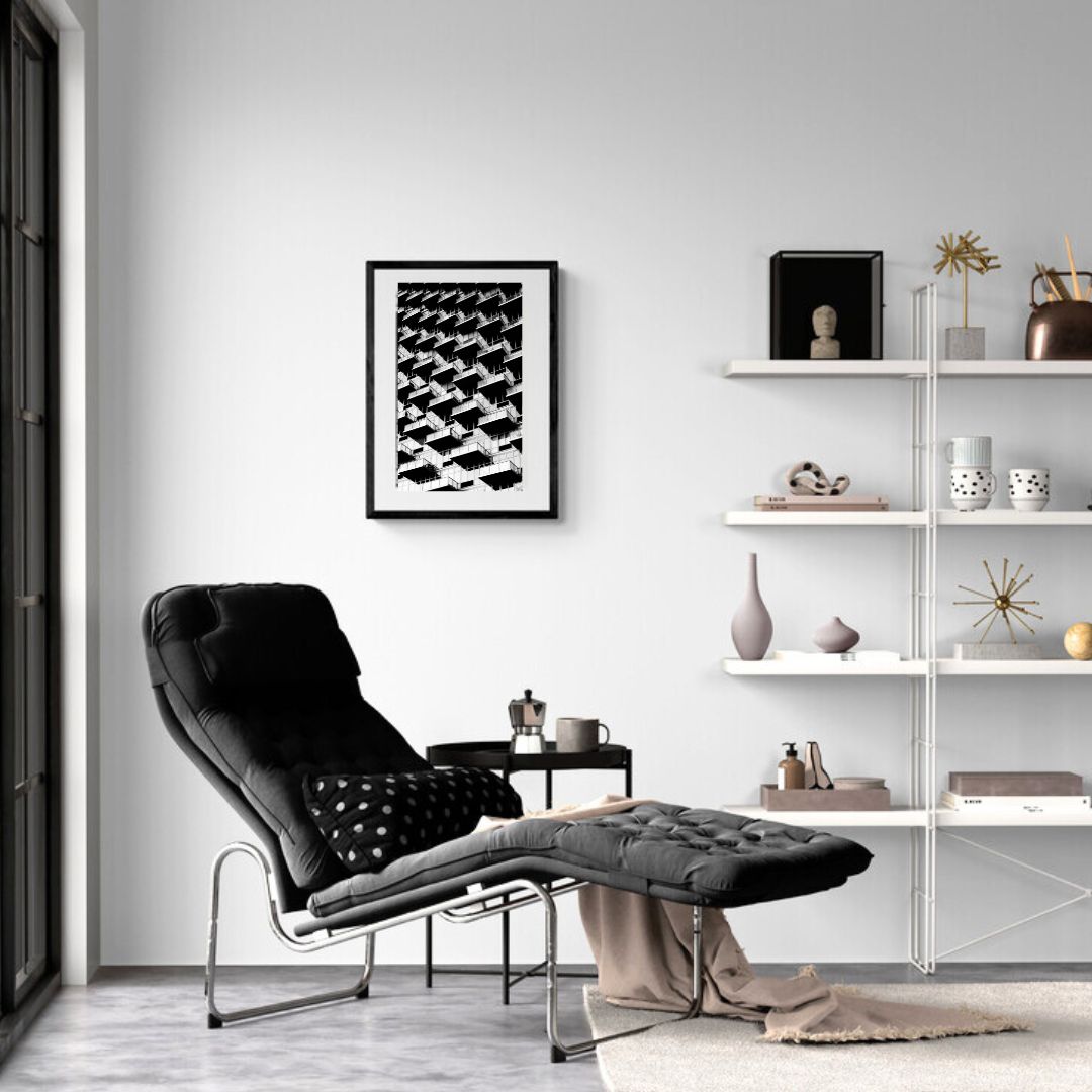 Modern living room with black armchair, white shelves, and abstract art on the wall.