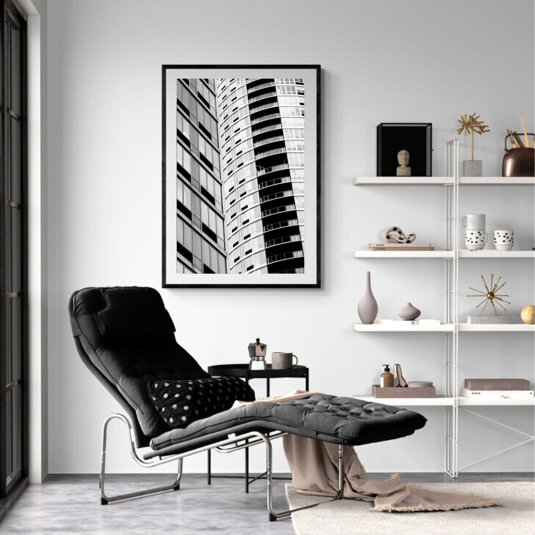 Modern living room with a black armchair, ottoman, and abstract art on the wall.