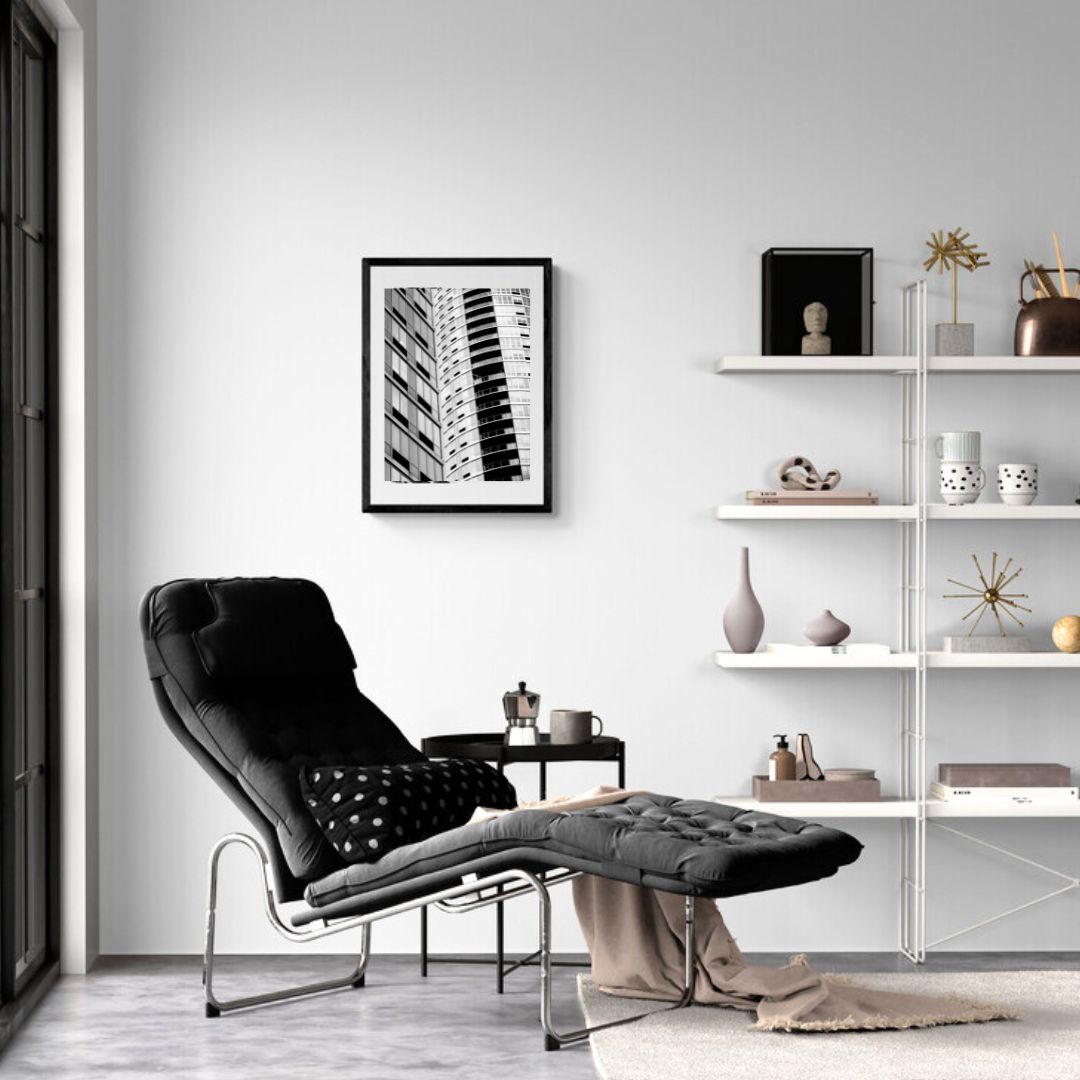 Modern living room with a black armchair, white shelves, and framed artwork.