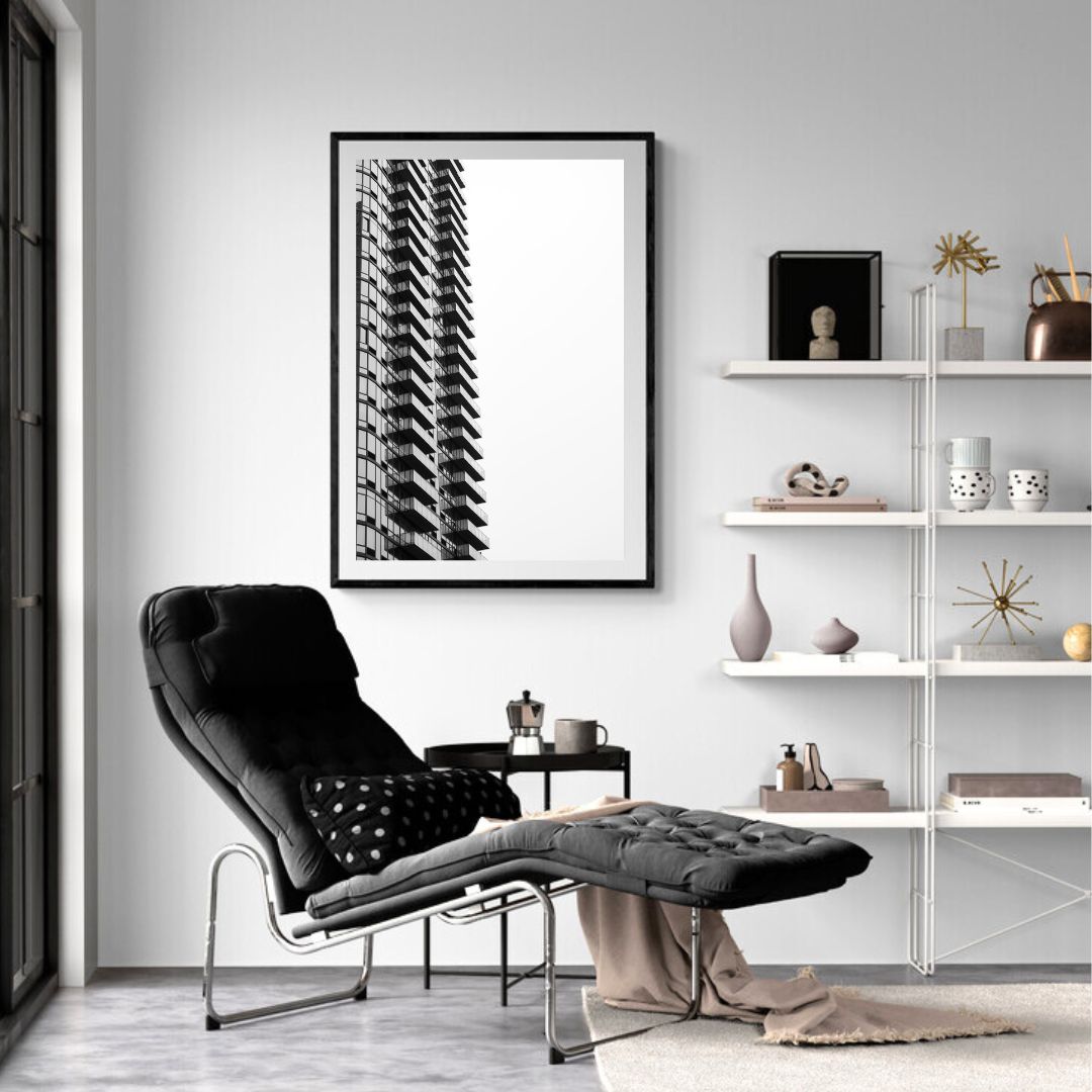 Modern living room with black armchair, ottoman, and abstract art on the wall.