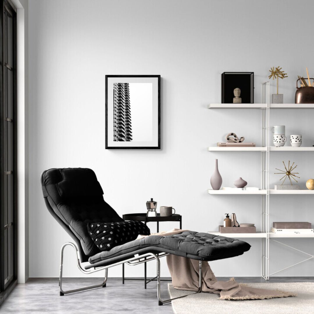 Modern living room with black armchair, white shelves, and framed artwork.