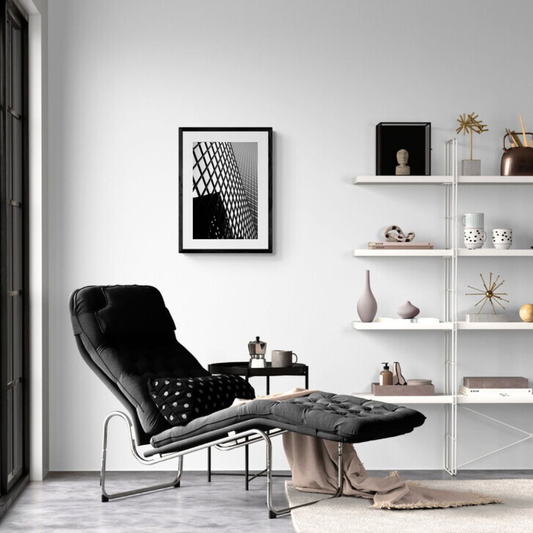 Modern living room with a black armchair, white shelves, and decorative items.