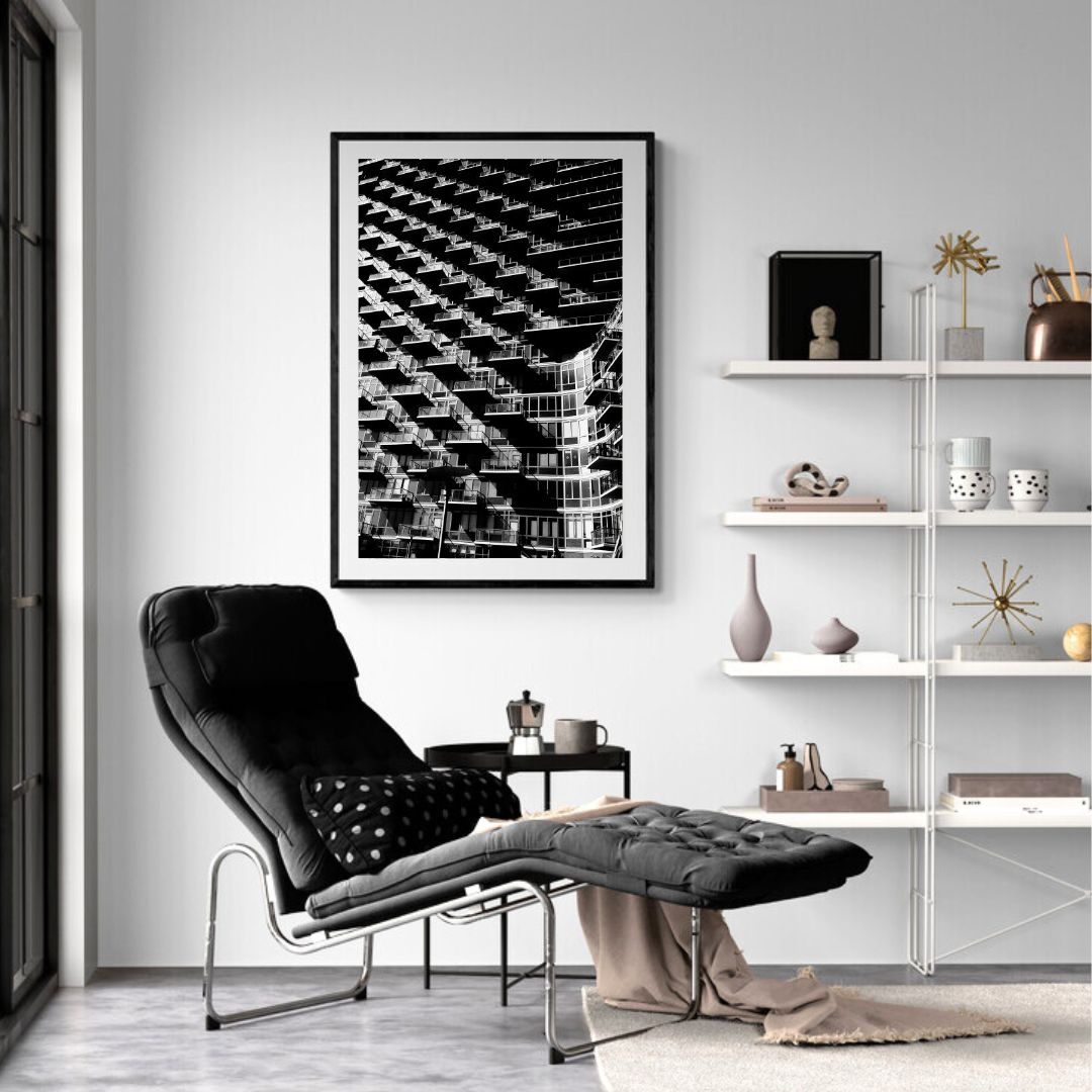 Modern living room with black armchair, ottoman, and abstract art on the wall.