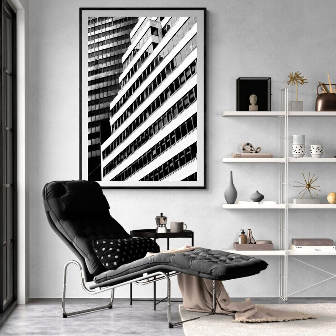 Modern living room with a black and white abstract art piece on the wall, a black armchair, and a white shelf.