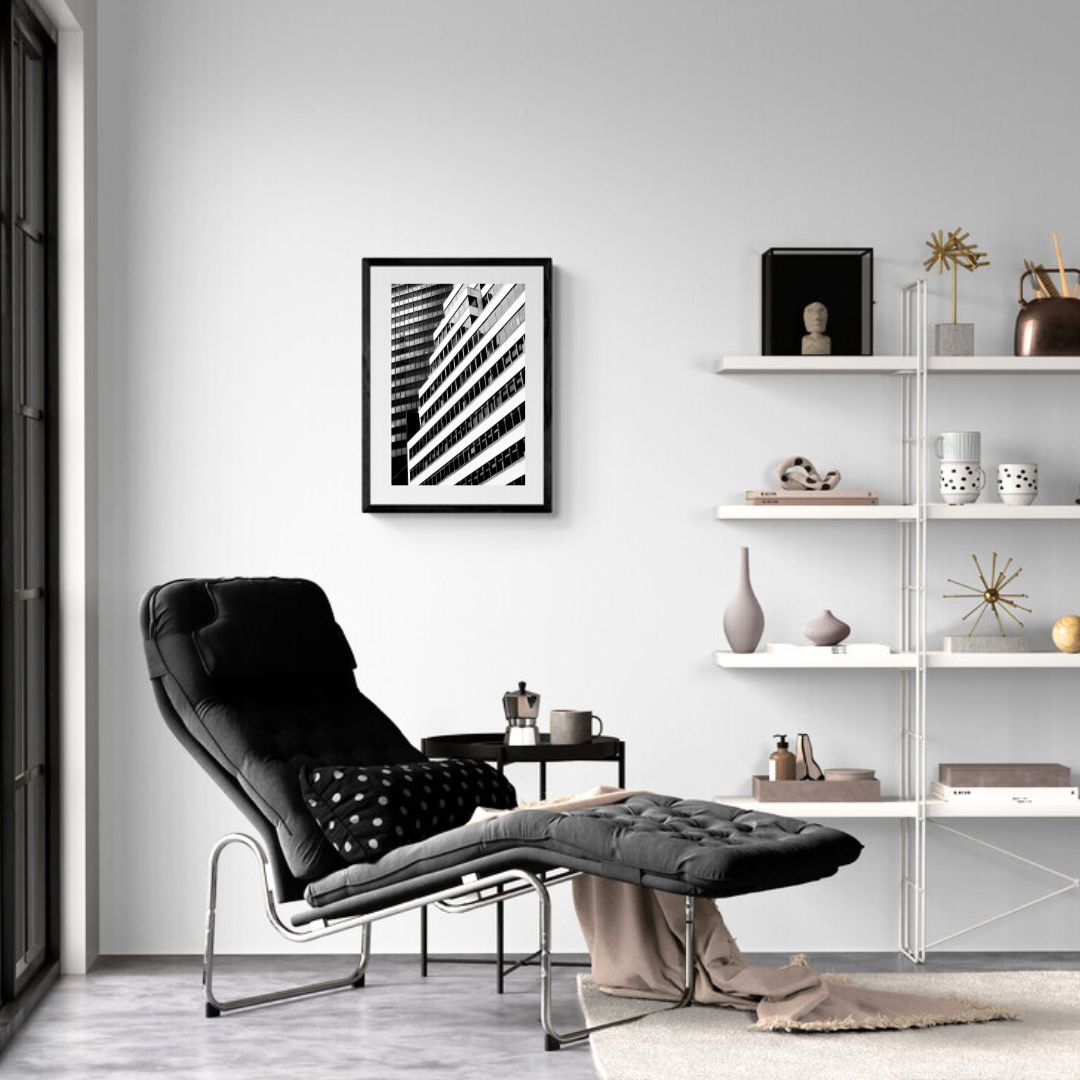 Modern living room with a black armchair, white shelves, and abstract art on the wall.