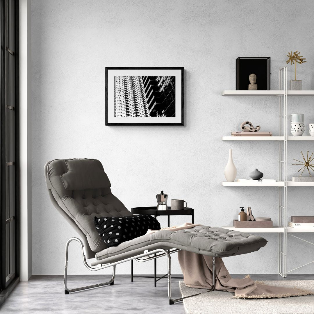 Modern living room with a gray lounge chair, ottoman, and shelves with decor items.
