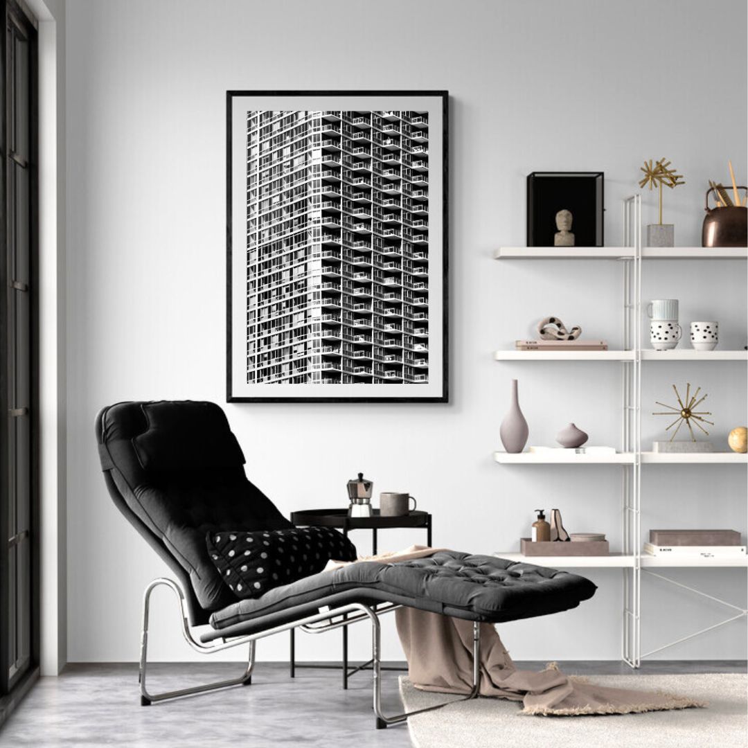 Modern living room with black armchair, ottoman, and wall art.