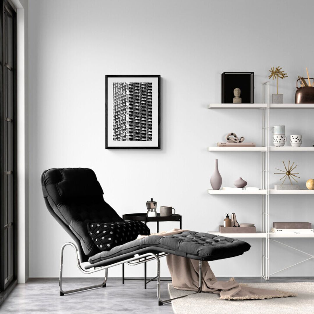 Modern living room with a black armchair, white shelves, and framed artwork.