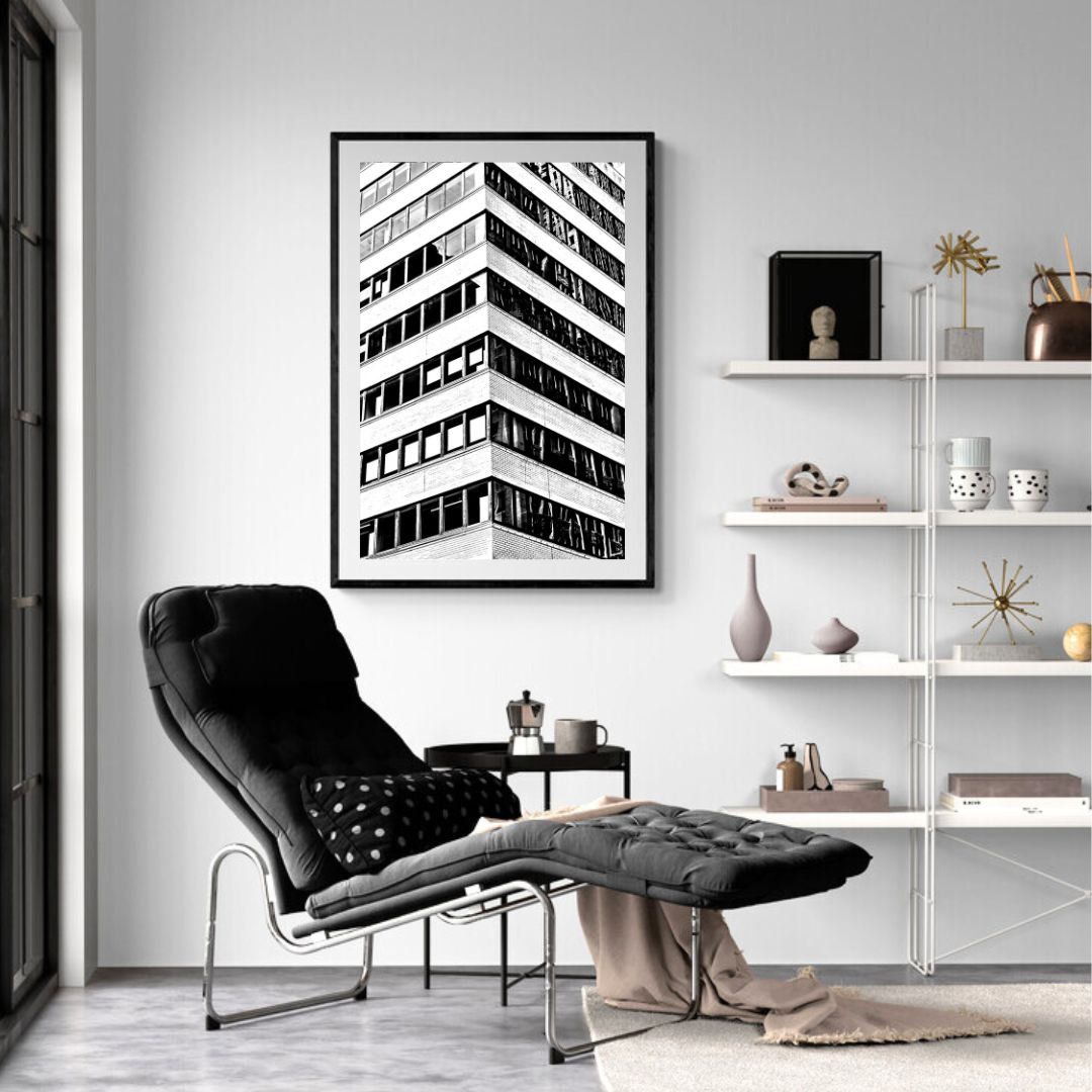 Modern living room with a black armchair, ottoman, and abstract art on the wall.