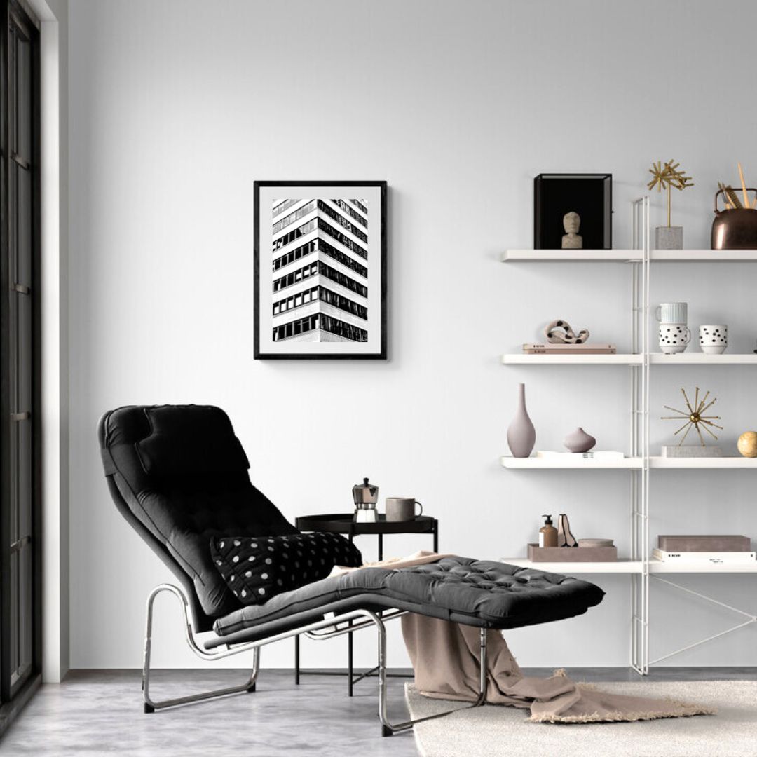 Modern living room with a black armchair, white shelves, and framed artwork.