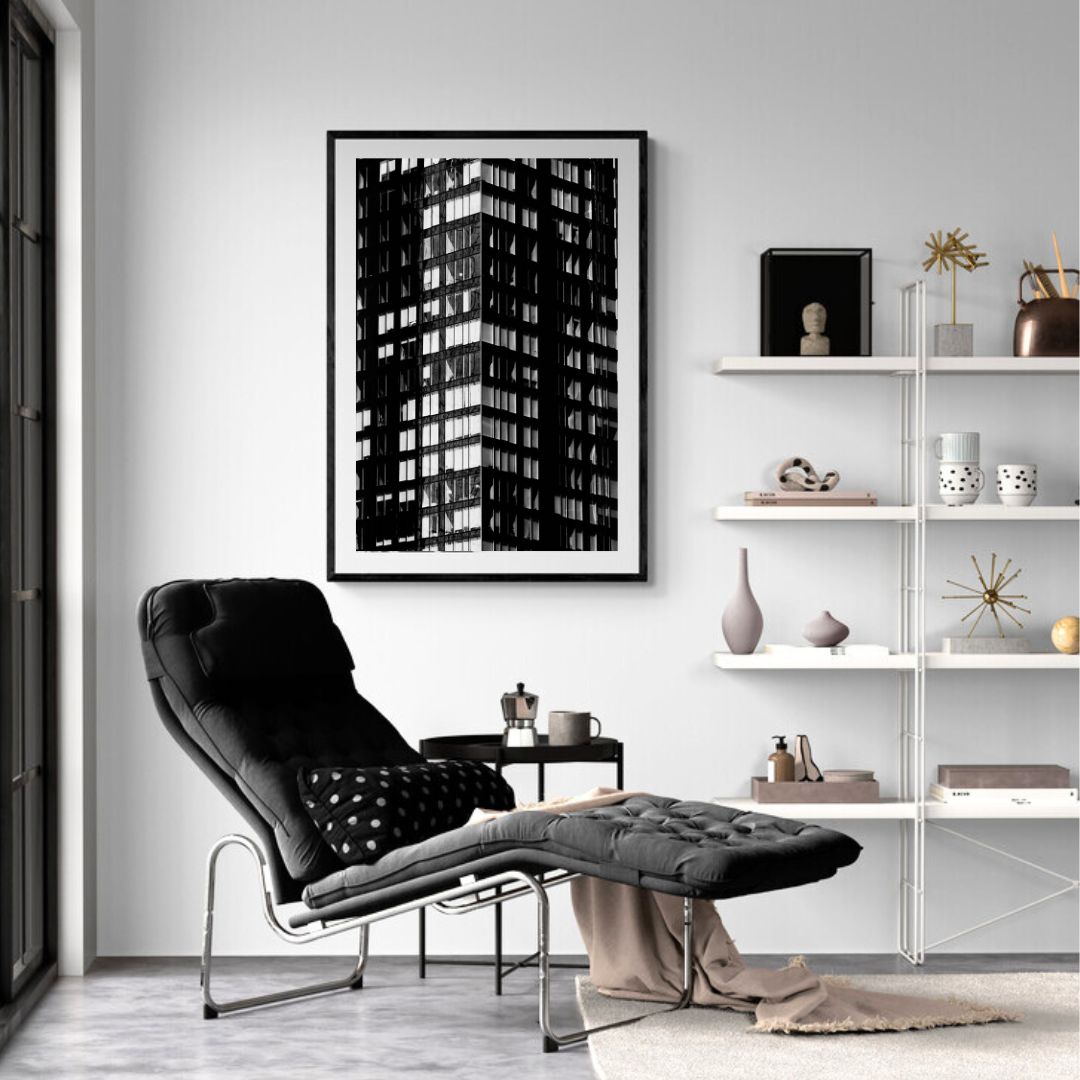 Modern living room with black armchair, white shelves, and framed artwork.