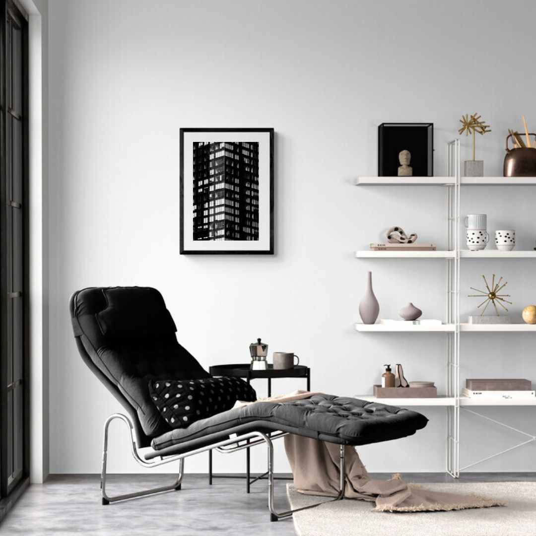 Modern living room with a black armchair, white shelves, and framed artwork.