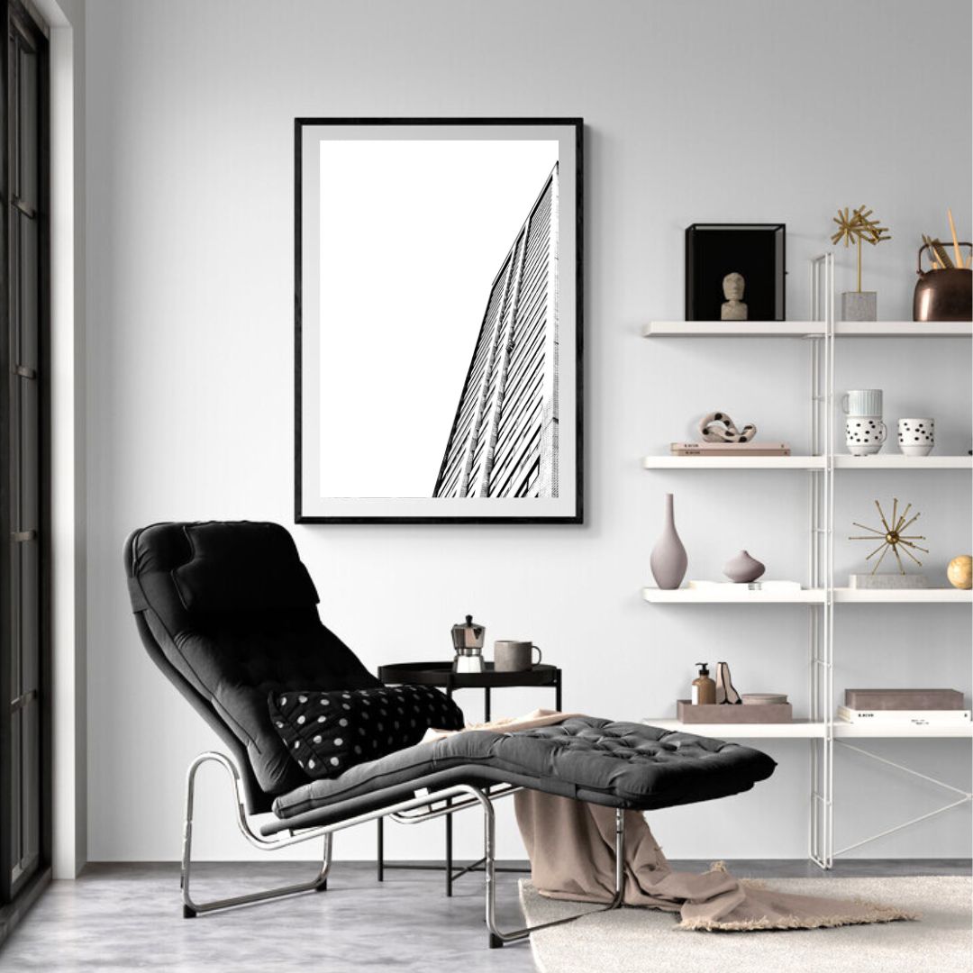 Modern living room with black armchair, ottoman, and abstract art on the wall.