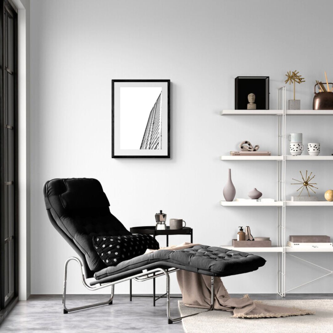 Modern living room with a black armchair, white shelves, and framed artwork.