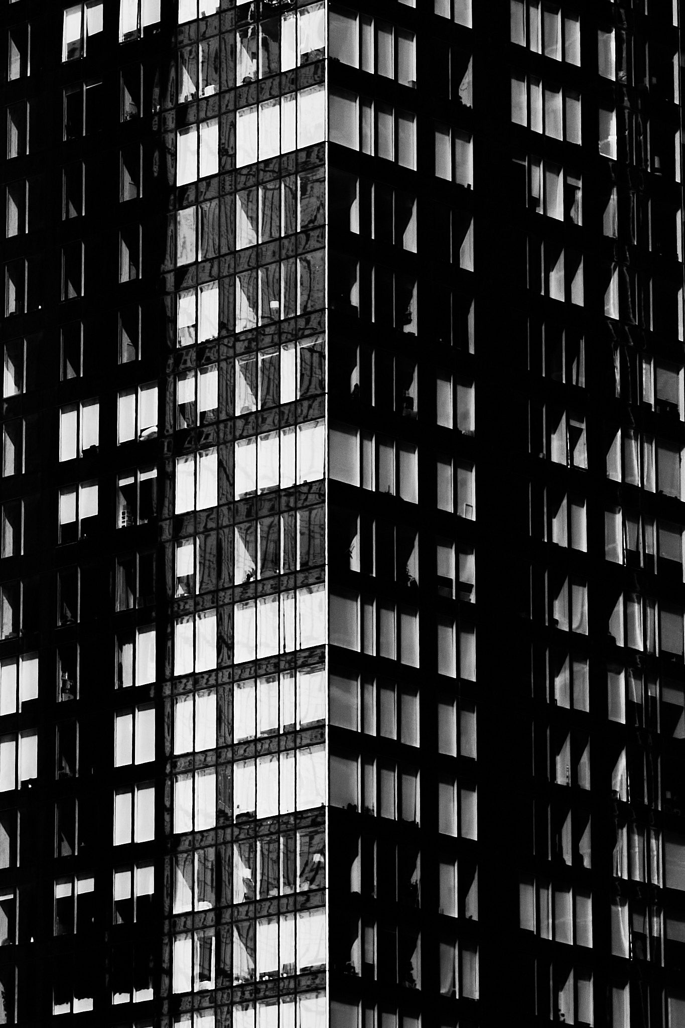 Black and white photo of a tall building with reflective windows
