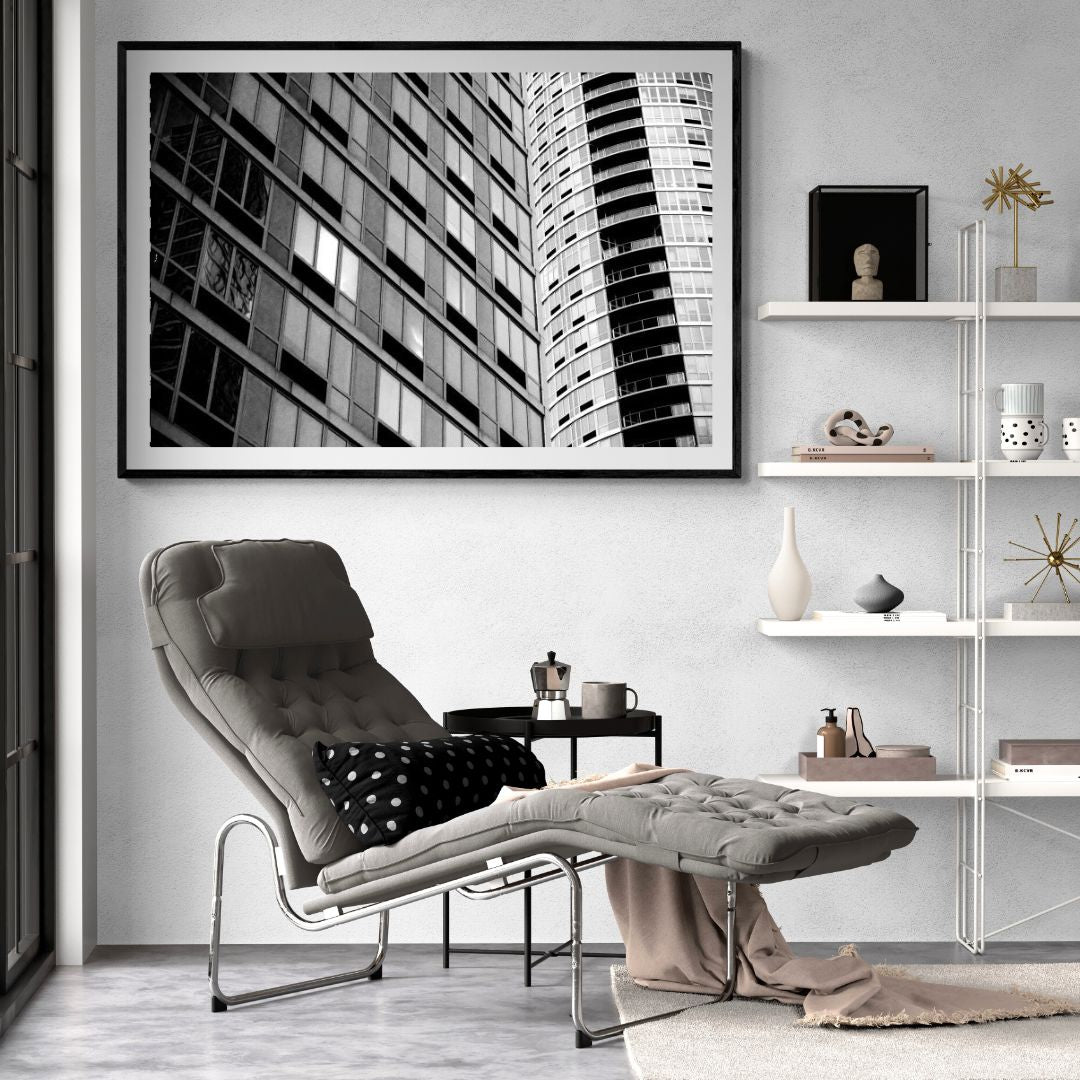 Modern living room with a gray armchair, coffee table, and cityscape artwork on the wall.