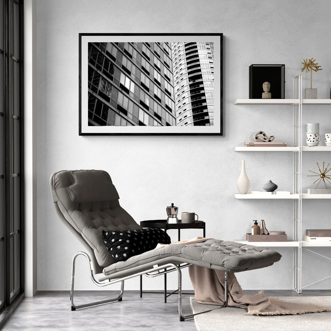 Modern living room with a gray armchair, ottoman, and cityscape artwork on the wall.