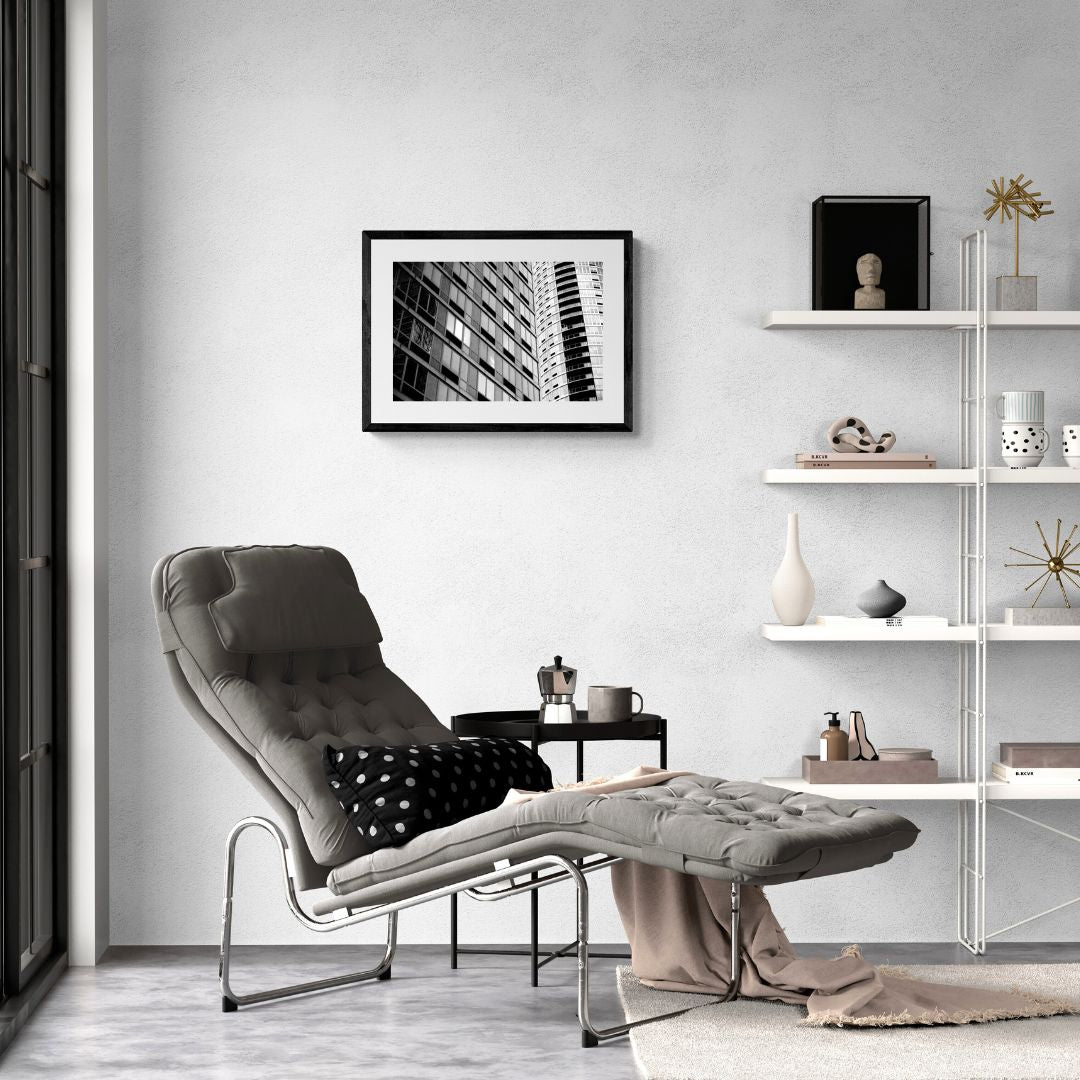 Modern living room with a gray lounge chair, ottoman, and shelves with decor items.