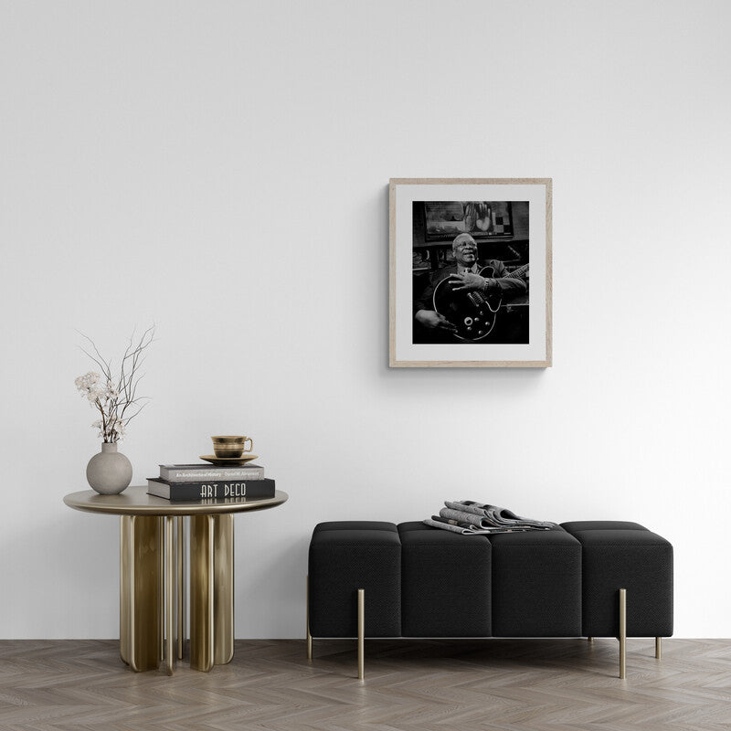 Modern living room with a black sofa, wooden side table, and framed black and white photo on the wall.