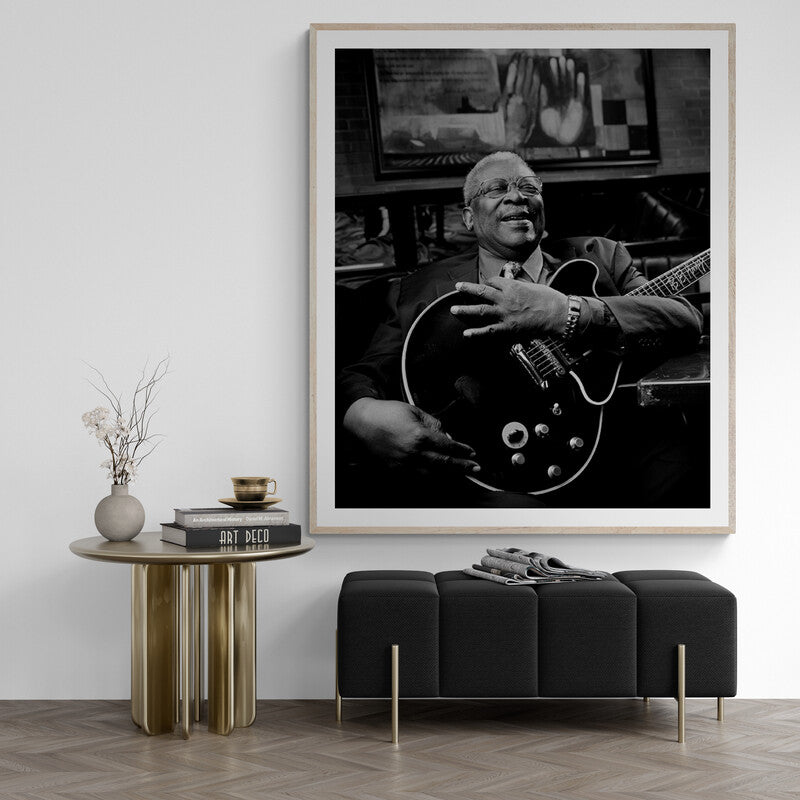 Framed black and white portrait of a musician playing guitar in a living room setting.