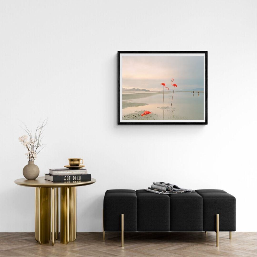 Modern living room with a black sofa, gold side table, and framed artwork on the wall.