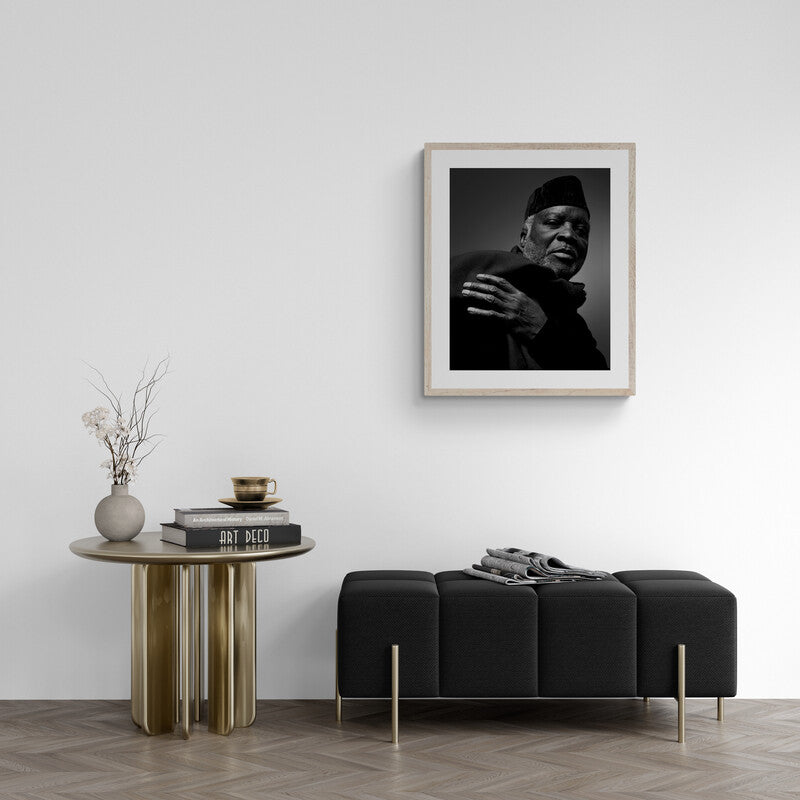 Framed black and white portrait above a modern black sofa and side table with decor items.
