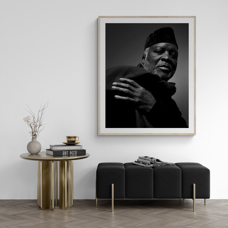 Framed black and white portrait of a man on a wall above a modern black sofa and side table.