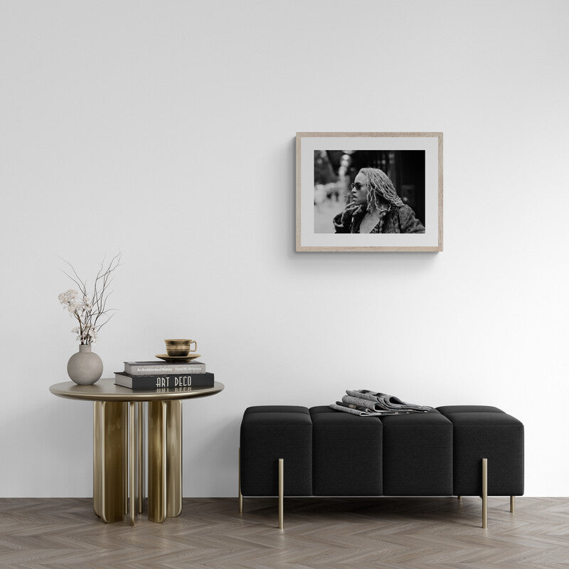 Modern living room with a black sofa, wooden side table, and framed photo on the wall.