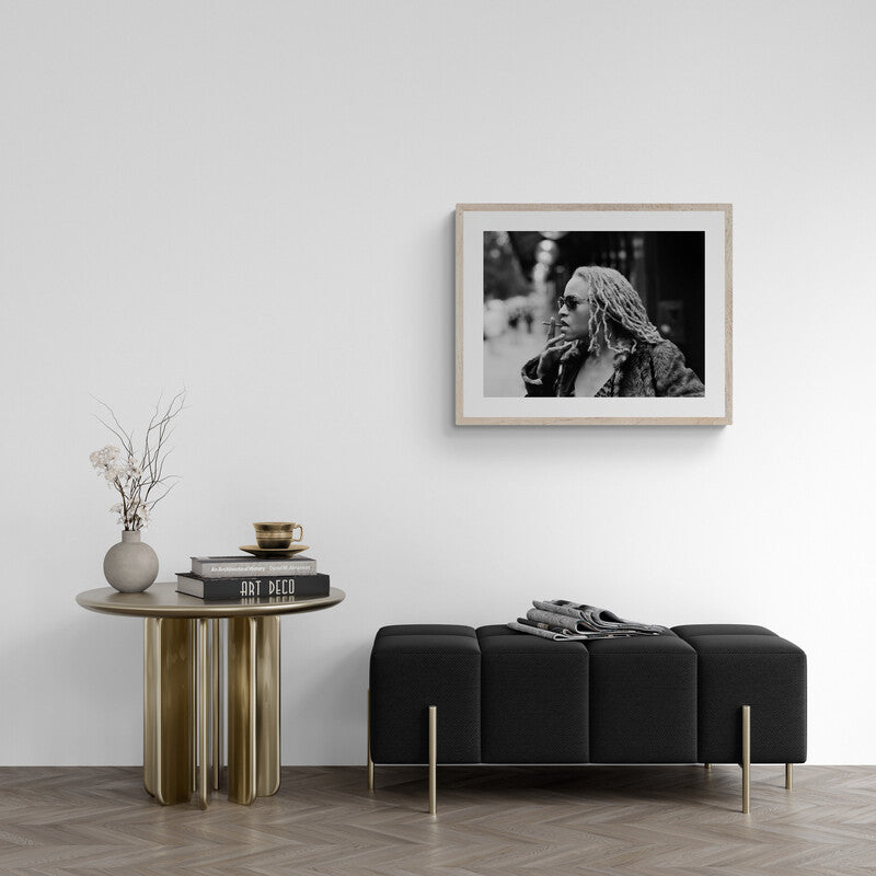 Modern living room with a black sofa, round wooden table, and framed black and white photo on the wall.