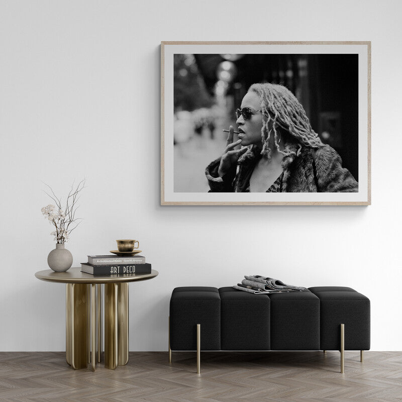 Framed black and white portrait on a wall above a modern living room setup with a sofa and side table.