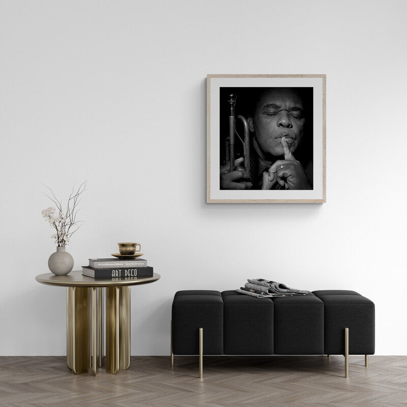 Framed black and white portrait above a modern black sofa and side table in a room.