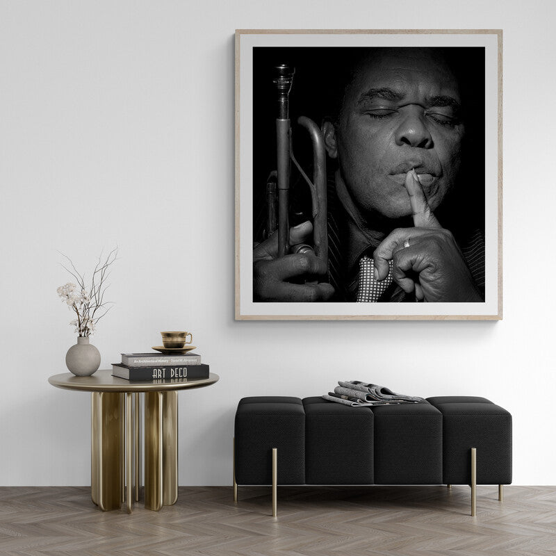 Framed black and white portrait of a musician with a trumpet above a modern living room setup.