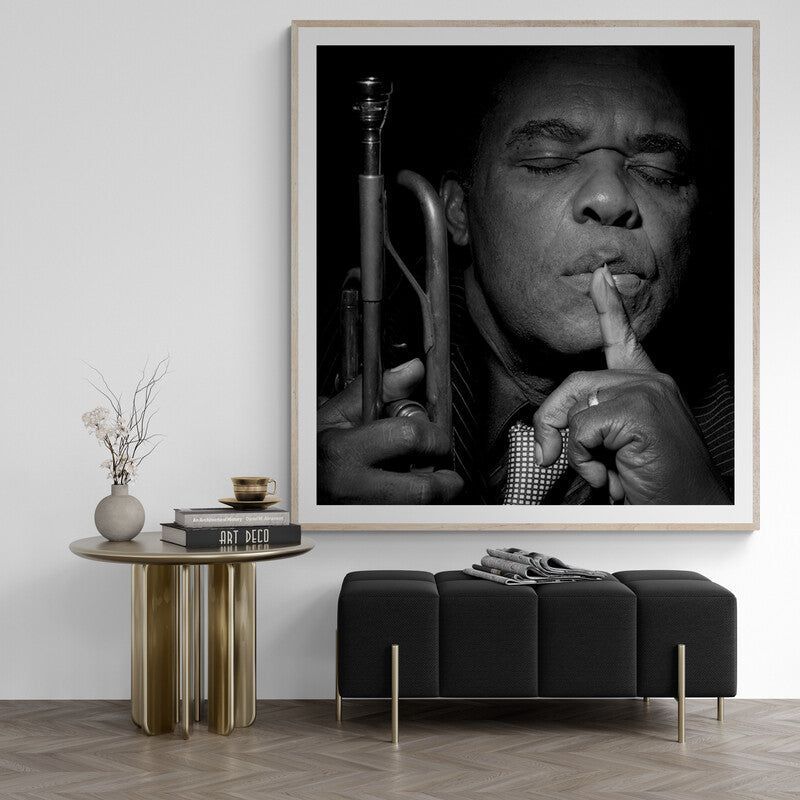 Framed black and white portrait of a musician with a trumpet in a modern interior setting.