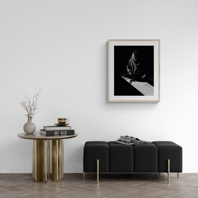 Modern interior with a black sofa, round wooden table, and framed artwork on a white wall.