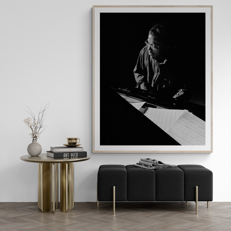 Framed black and white artwork of a person at a piano in a modern interior setting.