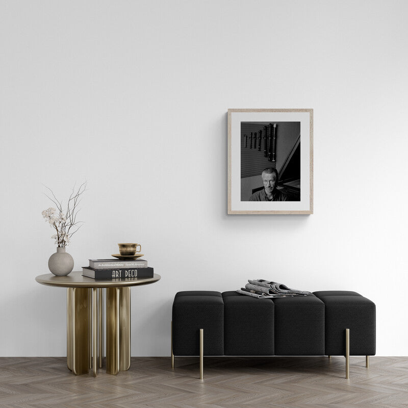Modern living room with a black sofa, wooden side table, and framed picture on the wall.