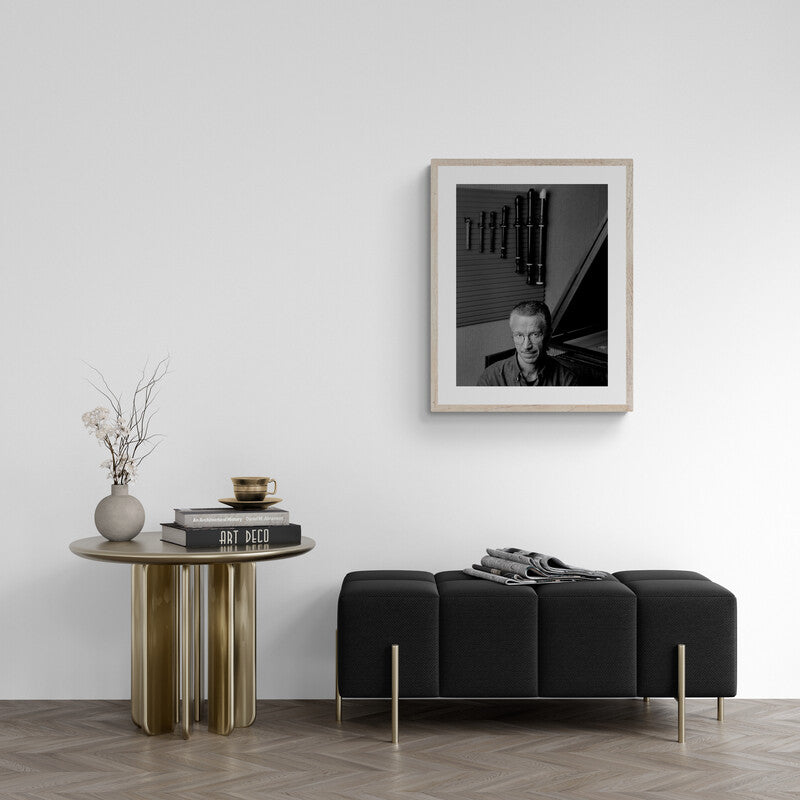 Modern living room with a black sofa, round wooden table, and framed portrait on the wall.