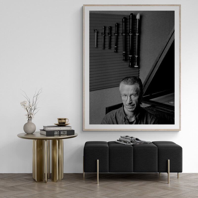 Framed black and white portrait of a man in a room with a piano and decor.